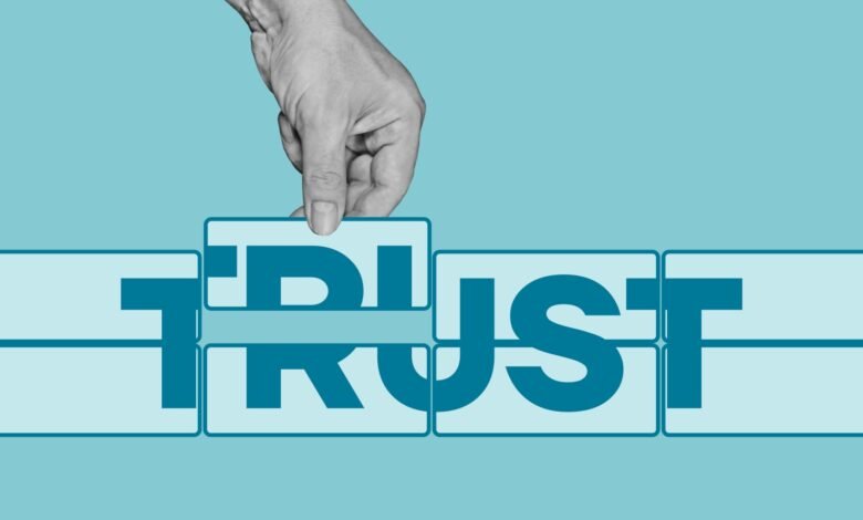Hand placing a puzzle piece completing the word TRUST. Teal and white color scheme.