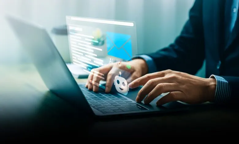Businessperson using AI-powered inbox on laptop, email and chatbot icons displayed.