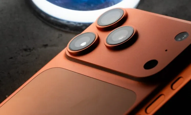 Close-up of a copper-colored smartphone's camera array, showcasing three lenses and a sleek design.