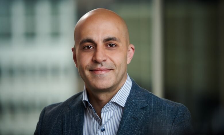 Headshot of Ali Ghodsi, Databricks CEO, smiling gently in a suit.