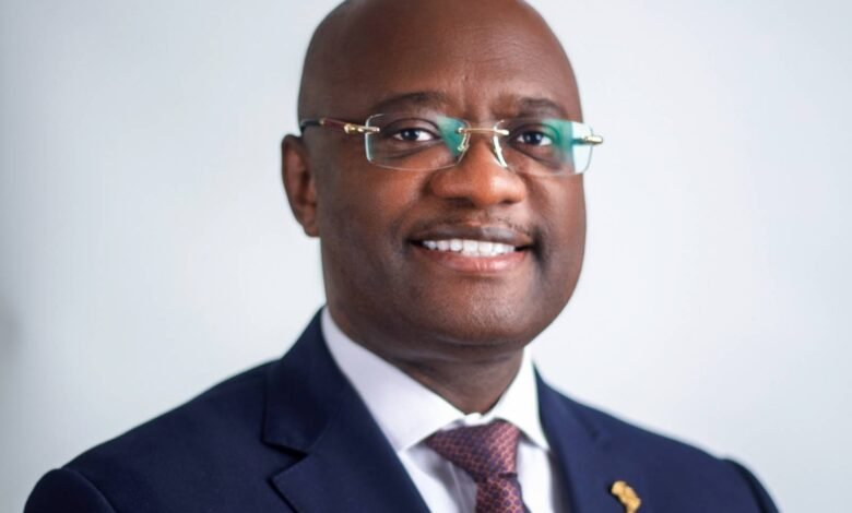Portrait of Dr. George Elombi, smiling and wearing a navy suit and glasses.