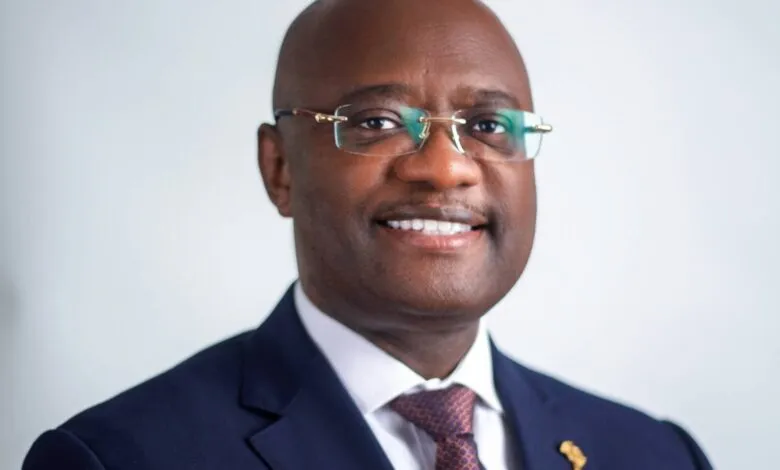Portrait of Dr. George Elombi, smiling and wearing a navy suit and glasses.