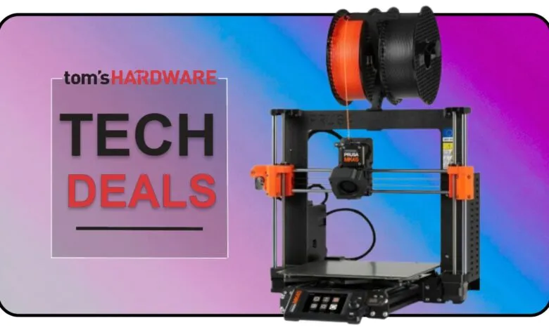 A 3D printer with orange and black filament spools on top, with 'Tom's Hardware Tech Deals' text overlay.
