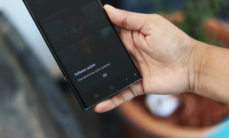 Hand holding a smartphone displaying a software update confirmation message.
