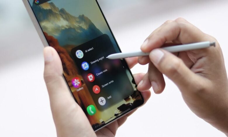 Hand using S Pen stylus on Samsung Galaxy S25 Ultra, accessing Air Command features like note creation and screen writing.