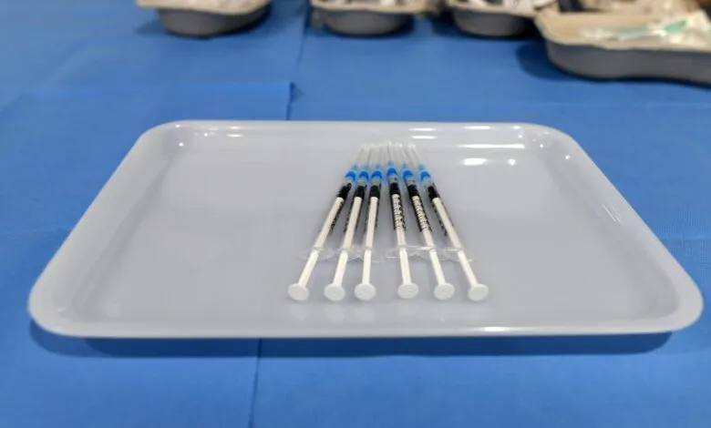 Six syringes arranged neatly on a white tray, ready for medical use.