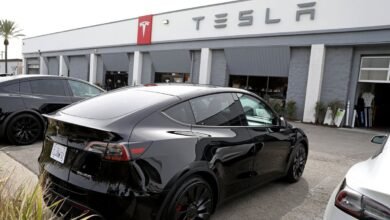 Black Tesla Model Y parked outside a Tesla dealership.