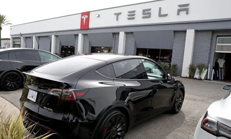 Black Tesla Model Y parked outside a Tesla dealership.