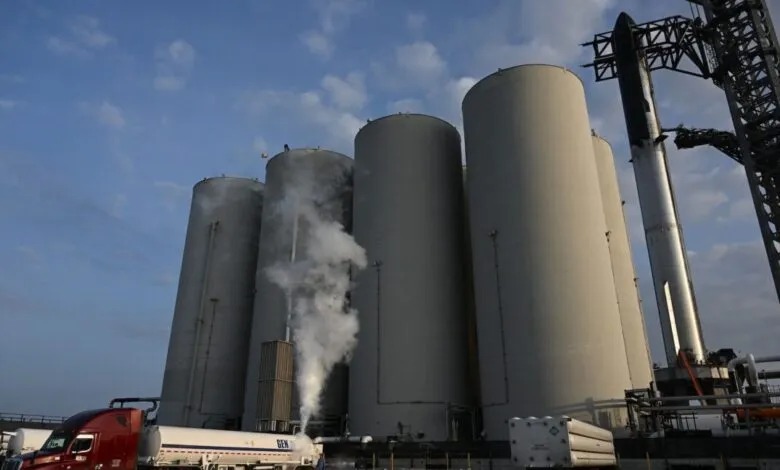SpaceX Starship rocket on launchpad, being fueled by a tanker truck. Large propellant tanks are visible.