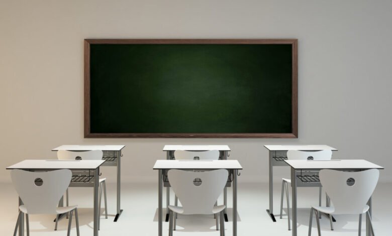 Empty modern classroom with white desks, chairs, and a green chalkboard.