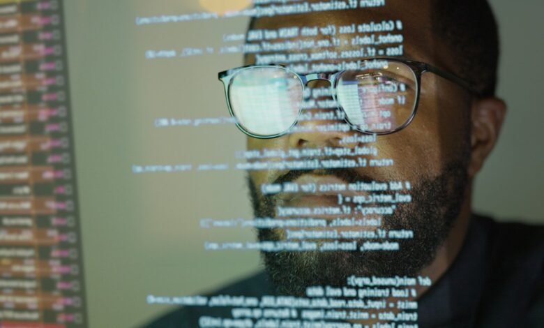 Close-up of a man's face, glasses reflecting lines of code, suggesting software development or coding.
