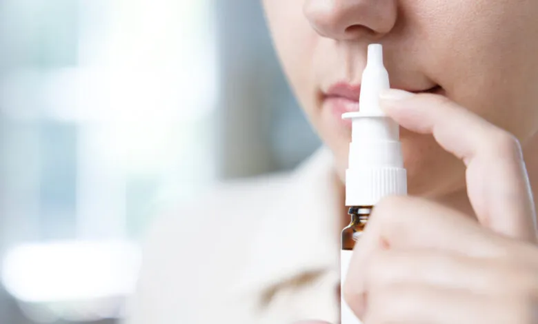 Close-up of a woman using a nasal spray, focusing on the application process.