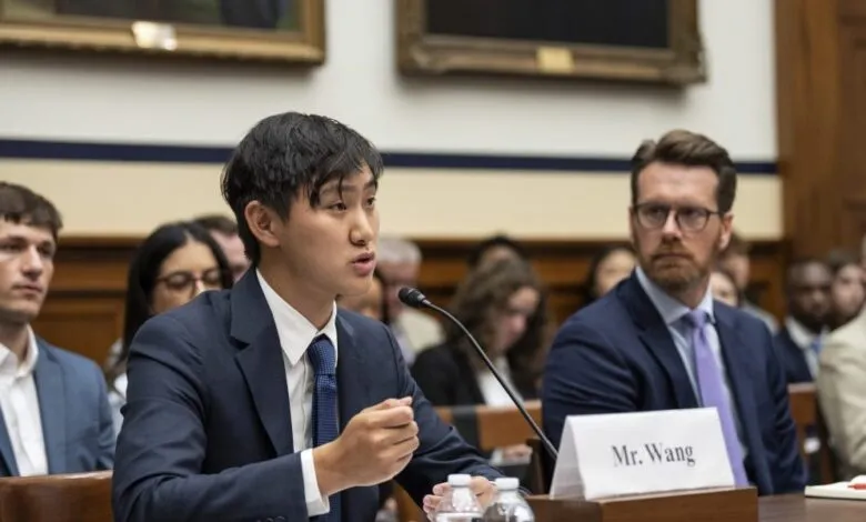 Mr. Wang testifies at a US Senate hearing, speaking into a microphone. Others in suits sit attentively.