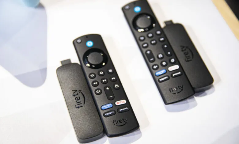 Two Amazon Fire TV remotes and streaming sticks on a white surface.