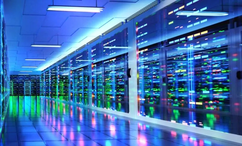 Modern data center with rows of illuminated servers, showcasing vibrant blue, green, and pink lights reflecting on a polished floor.