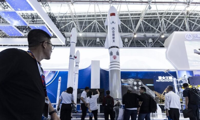 Long March rocket models displayed at the China International Aviation & Aerospace Exhibition in Zhuhai, China. People view the exhibit.