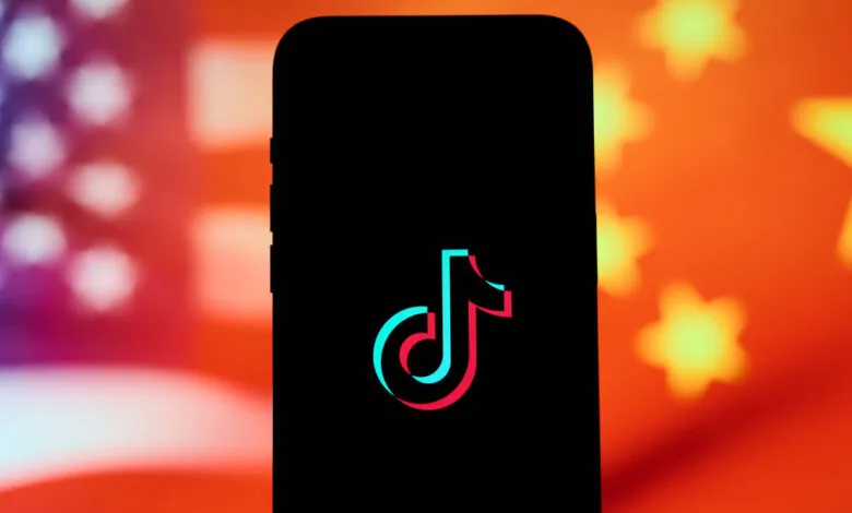 TikTok logo on a phone screen with blurred US and Chinese flags in the background.