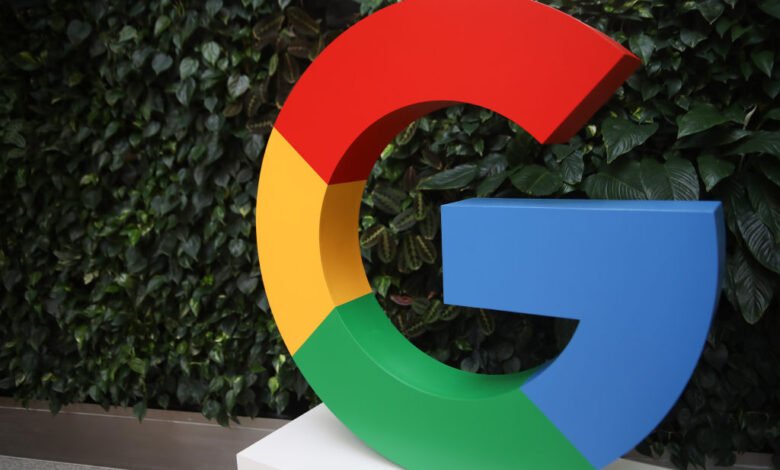 Large Google logo in red, yellow, green, and blue, displayed against a lush green wall.