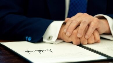 Close-up of Donald Trump's hands clasped over a document with his signature.