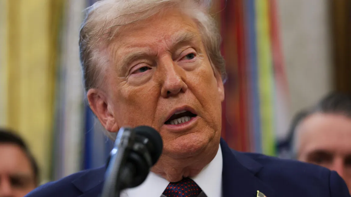 Close-up of President Donald Trump speaking at a podium in the Oval Office.