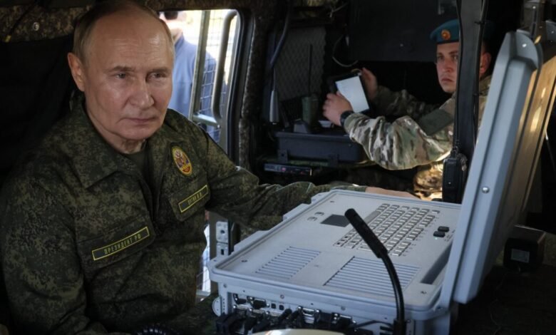 Vladimir Putin in military uniform inside a vehicle, looking at equipment.