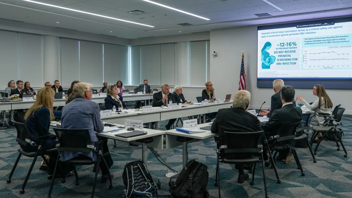 CDC immunization committee meeting in Chamblee, Georgia, attendees seated at tables, presentation on Hepatitis B vaccination.