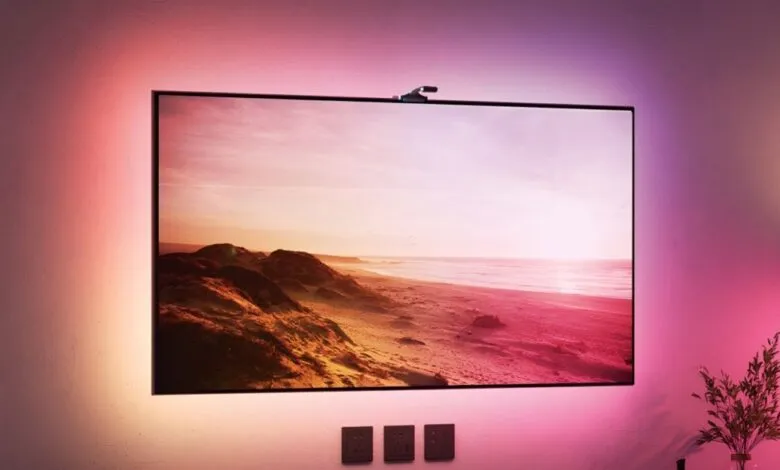 Govee TV backlight illuminates a wall with pink and purple hues, enhancing a beach scene on the screen.
