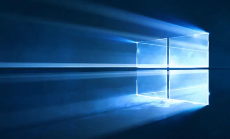 The Windows logo illuminated by bright blue light beams against a dark blue background.