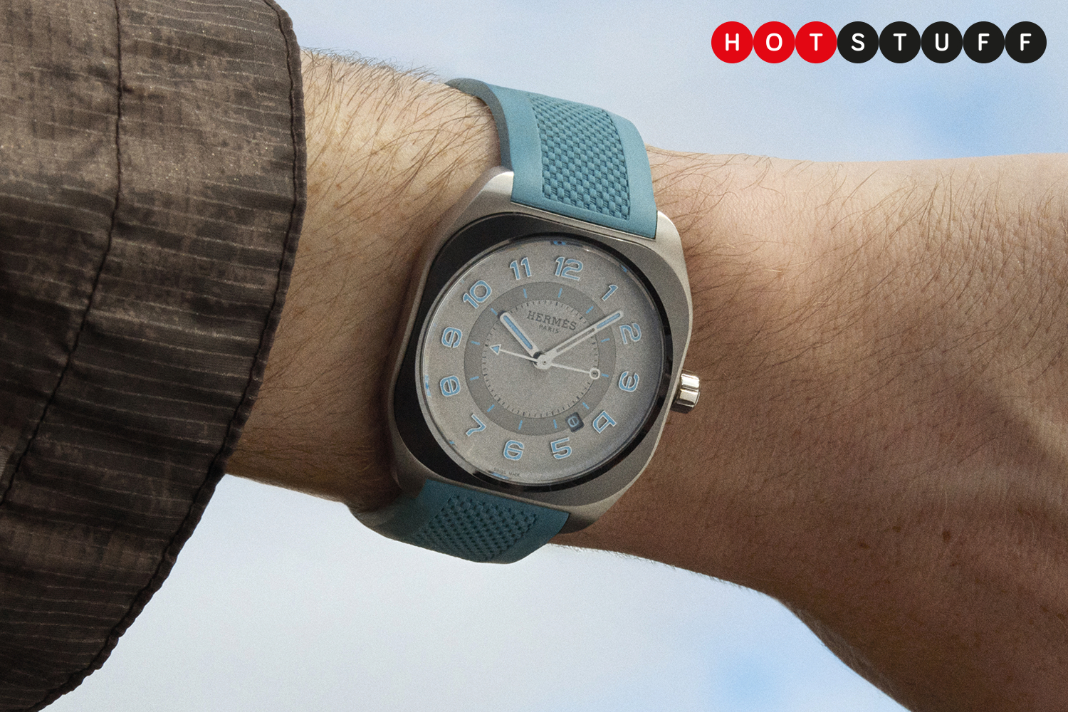 Close-up of a man's wrist wearing a stylish Hermès H08 watch with a teal rubber strap.