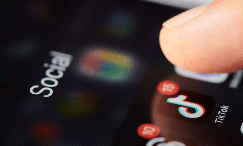 Close-up of a finger about to tap the TikTok app icon on a smartphone screen.