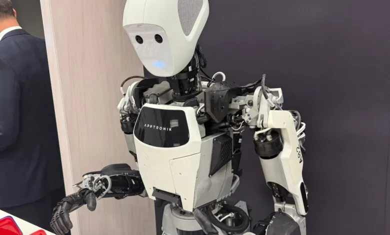 Close-up of a white and black humanoid robot with a smooth helmet and visible internal mechanics.