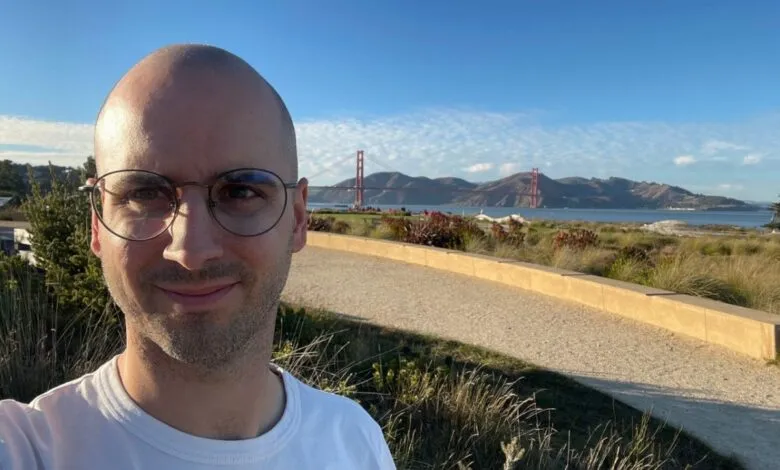 Man with glasses smiles at the camera with the Golden Gate Bridge in the background.