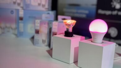 Two smart bulbs, one round and one GU10, displayed on white cubes. Soft pink lighting.