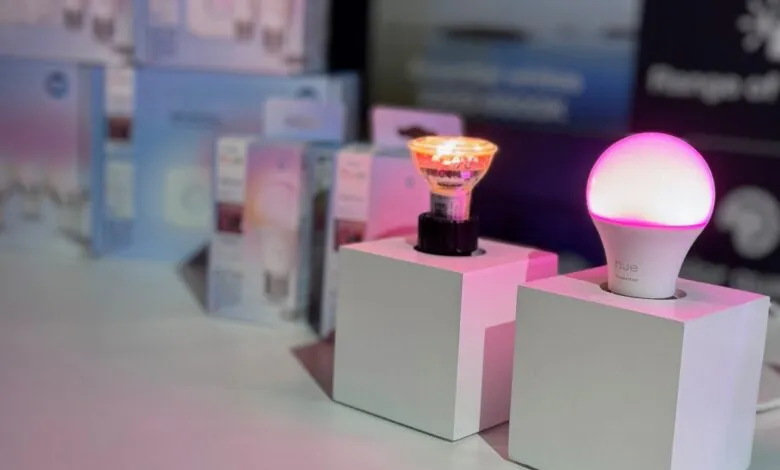 Two smart bulbs, one round and one GU10, displayed on white cubes. Soft pink lighting.