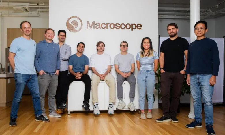 Macroscope team members posing in a modern office with the company logo.