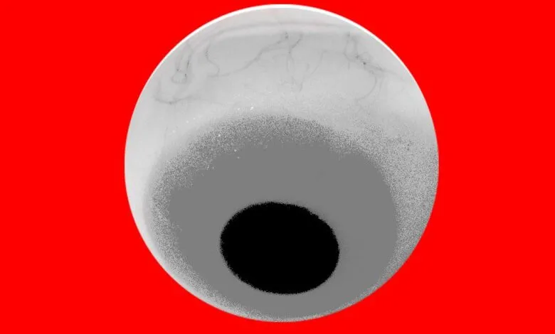 Close-up of a grayscale eyeball with a black pupil against a vibrant red background.