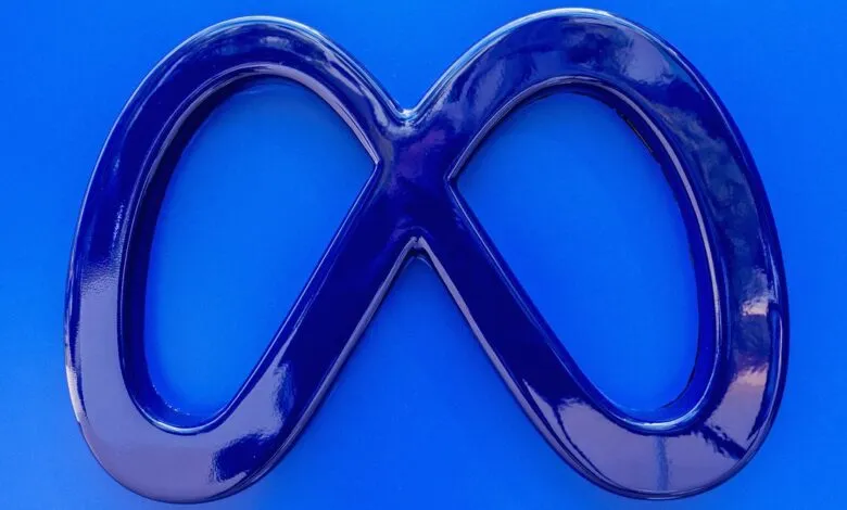 Close-up of a dark blue, infinity-symbol logo against a bright blue background.