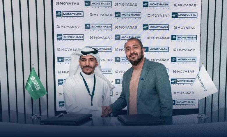 Two men shake hands at a Moyasar and MoneyHash partnership event. A Saudi Arabian flag is visible.
