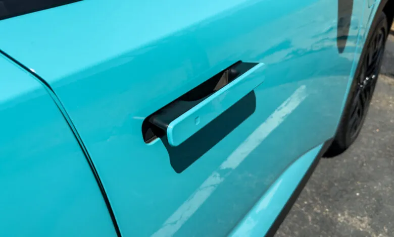 Close-up of a teal Nissan Leaf's flush door handle, showcasing its sleek, modern design.