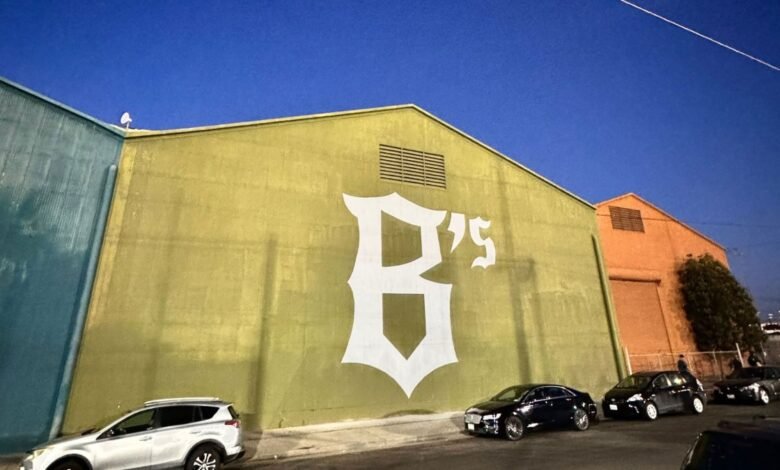 Large white 'B's' logo painted on an olive-green building wall in Oakland.