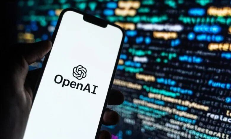 Close-up of a smartphone displaying the OpenAI logo against a blurred background of computer code.