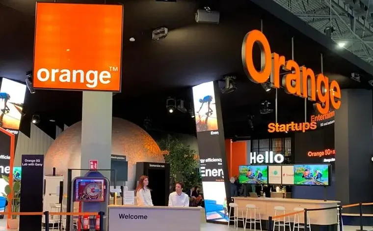 Orange telecommunications company booth with large signage and interactive displays.