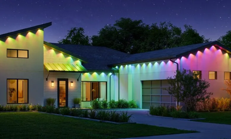 Modern house at night illuminated with colorful LED lights along the roofline and walls.