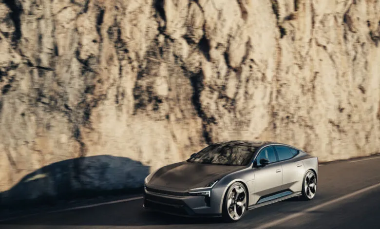 Sleek, silver electric car driving along a road next to a rocky cliff face.