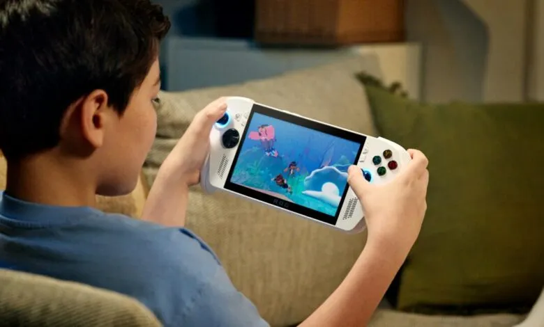 A young boy plays a video game on a handheld console while sitting on a couch.