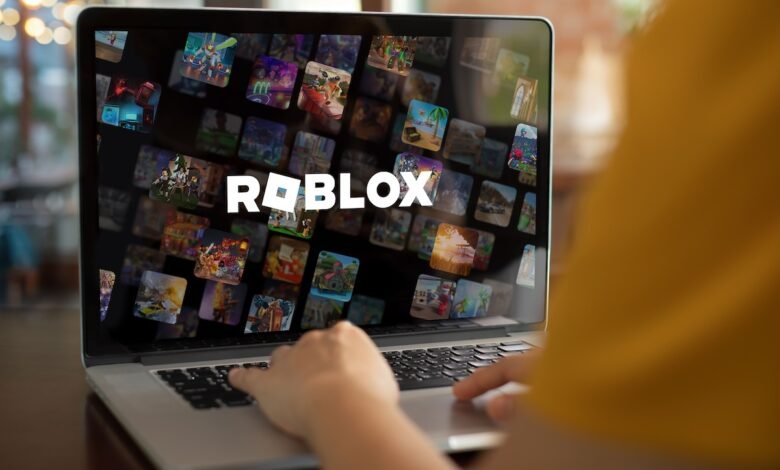 Person using laptop to play Roblox, showcasing a screen filled with various game thumbnails.