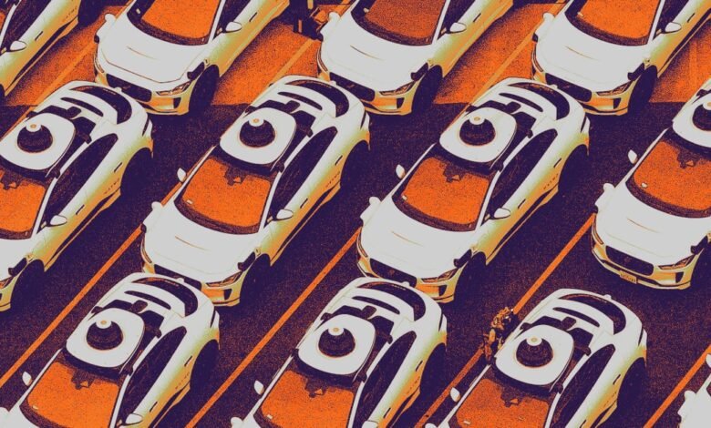 Overhead view of numerous white self-driving cars in a parking lot, featuring a distinctive circular sensor on each roof.