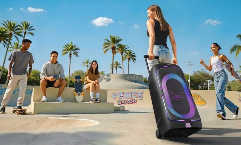 Portable Bluetooth speaker with vibrant light show, being wheeled by a young woman at a skate park with friends.