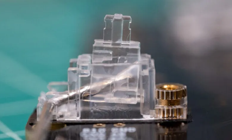 Close-up of a clear plastic connector with metallic pins on a circuit board.