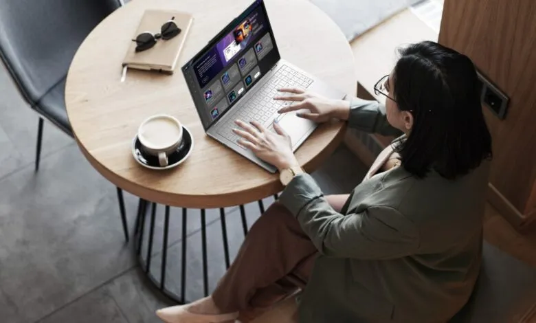 Woman works on laptop in cafe, showcasing apps and a modern interface.